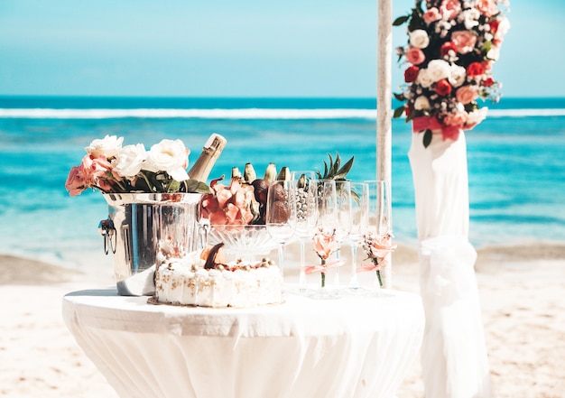 mesa elegante de boda con frutas tropicales y pastel en la playa