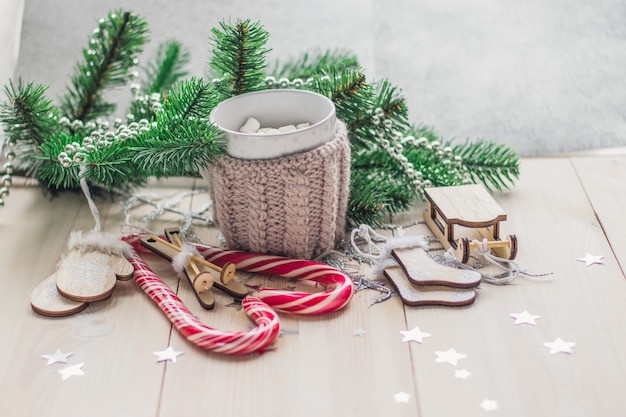 Mesa de madera cubierta de bastones de caramelo, malvaviscos y adornos navideños bajo las luces