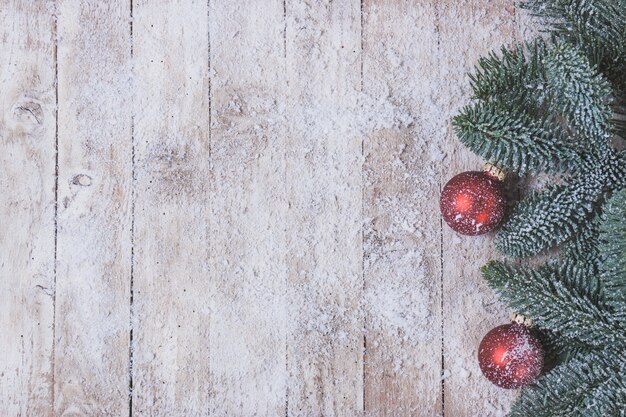 Mesa de madera con hojas de pino y bolas de navidad