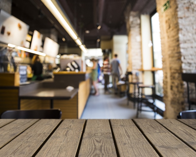 Foto gratuita mesa de madera mirando hacia bar con ventanas grandes