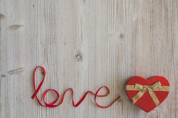 Mesa de madera con la palabra "love" y una caja con forma de corazón