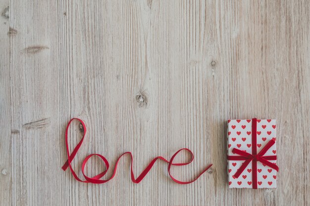 Mesa de madera con la palabra "love" y una caja de regalo