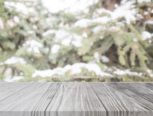 Mesa de madera vacía frente a árbol de navidad con nieve