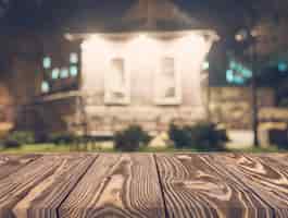 Foto gratuita mesa de madera vacía frente a telón de fondo casa borrosa
