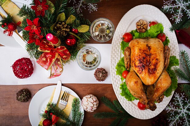 Mesa navideña servida con pavo, decorada con brillantes guirnaldas y velas.