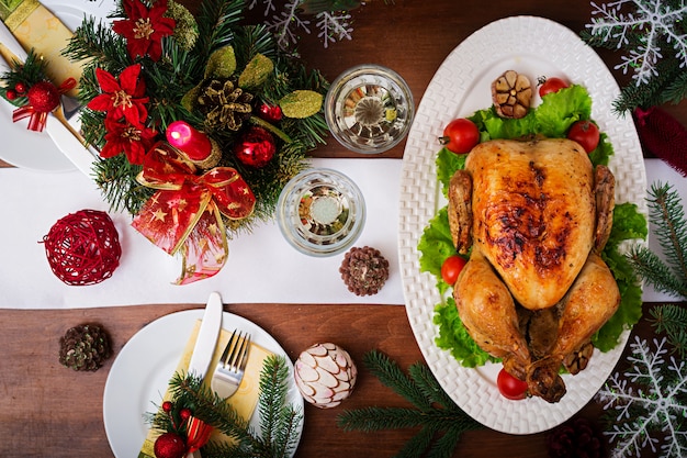 Mesa navideña servida con pavo, decorada con brillantes guirnaldas y velas.