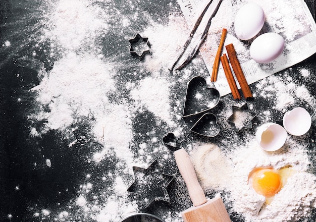 Mesa negra llena de harina y huevos con adornos navideños