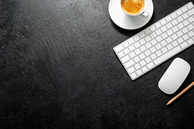 Mesa de oficina con taza de café, teclado y bloc de notas