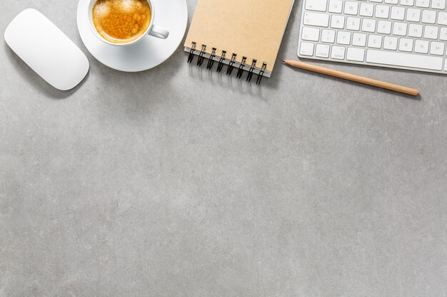 Mesa de oficina con taza de café, teclado y bloc de notas