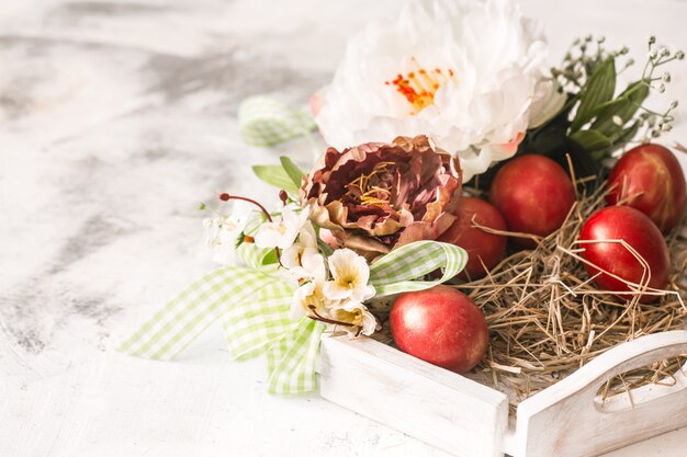 Mesa de Pascua con una canasta y huevos rojos con flores