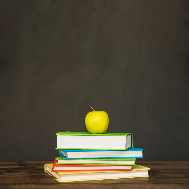 Mesa con pila en libros y manzana