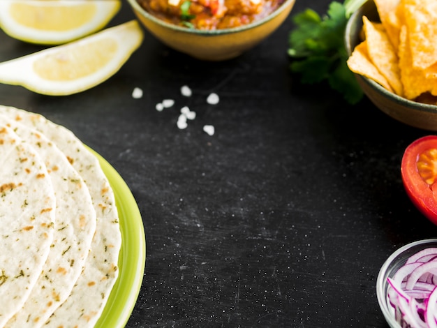 Mesa con quesadilla, nachos y verduras.