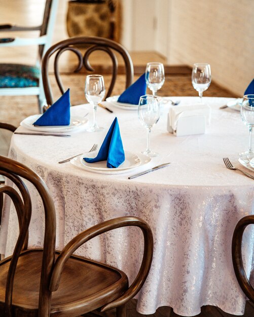 Mesa de restaurante con mantel de encaje blanco y servilletas azules