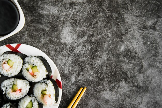 Mesa con rollos de sushi, salsa de soja y palillos de madera.