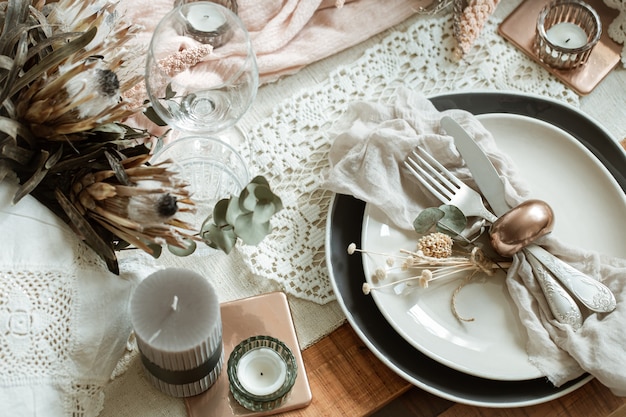 Mesa romántica con velas encendidas y flores secas para la boda con muchos detalles decorativos.