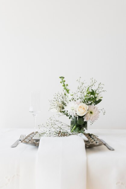 Mesa con texto de amor y florero.