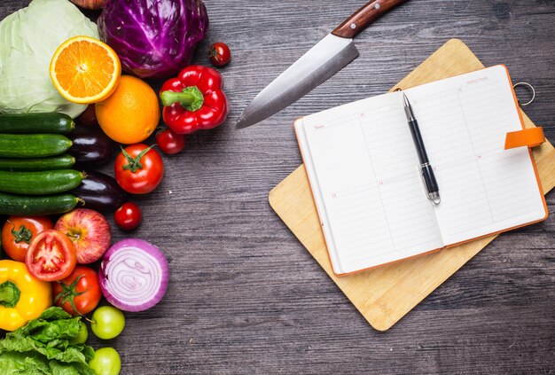 Mesa con verduras, un cuchillo y un cuaderno