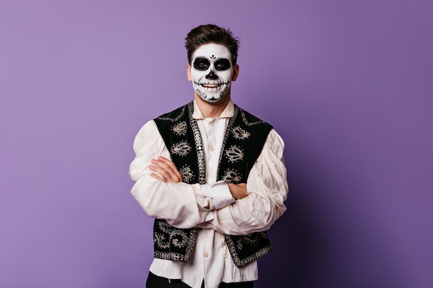 Mexicano alegre en traje tradicional está sonriendo. Retrato de hombre en pared lila.