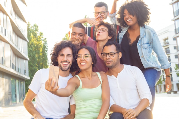 Foto gratuita mezcla alegre corrió personas tomando selfie grupal