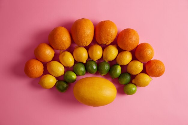 Mezcla de cítricos frescos maduros dispuestos alrededor de un melón amarillo en semicírculo. Alimentos crudos ricos en vitaminas y nutrientes. Surtido de frutas. Vista superior y endecha plana. Alimentación saludable, cosecha, concepto de dieta