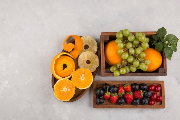 Mezcla de frutas y bayas en platos de madera en espacios en blanco
