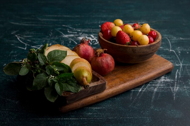 Mezcla de frutas en un plato de madera aislado en espacio azul