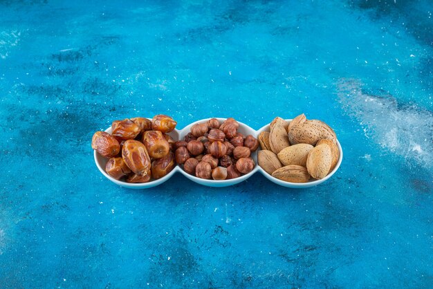 Una mezcla de nueces en un cuenco, sobre la mesa azul.