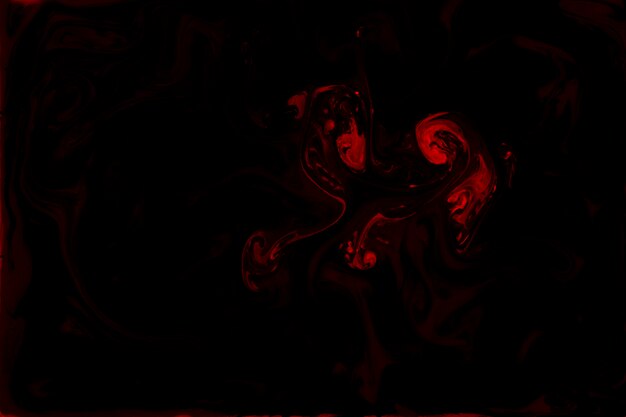Mezcla de pinturas acrílicas rojas sobre fondo negro.