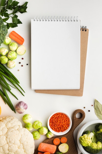 Foto gratuita mezcla plana de verduras con cuaderno en blanco