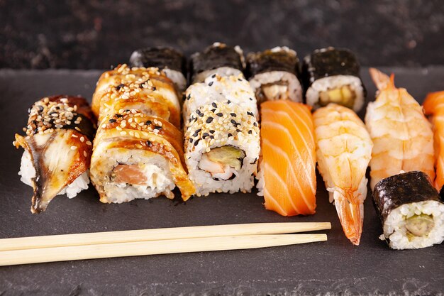 Mezcla de variedad de rollos de sushi sobre fondo negro en foto de estudio