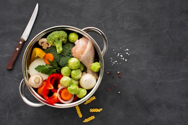 Mezcla de verduras y muslo de pollo en una sartén con espacio de copia