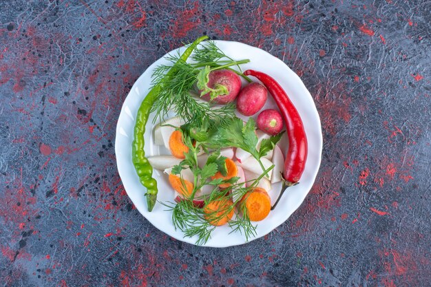 Mezcla de verduras en un plato blanco sobre mesa negra.