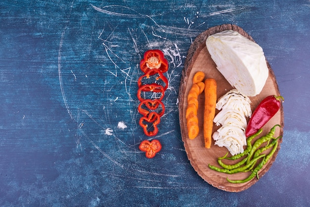 Mezcla de verduras en un plato de madera en el espacio azul.