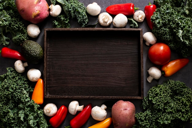 Foto gratuita mezcla de verduras de vista superior con bandeja de madera vacía