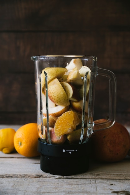 Foto gratuita mezclador lleno de mezcla de frutas en mesa de madera