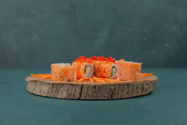 Mezclar sushi con rodajas de zanahoria sobre tabla de madera.