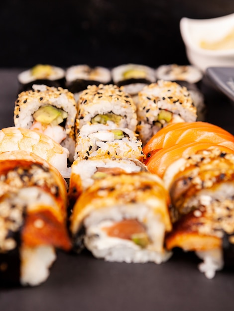 Mezclar variedad de rollos de sushi sobre fondo de piedra negra en estudio