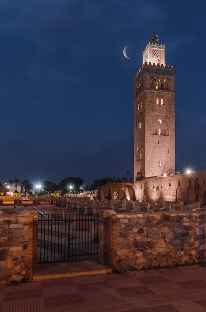 Mezquita Koutoubia en la noche brillando bajo la luna creciente en Marrakech, Marruecos