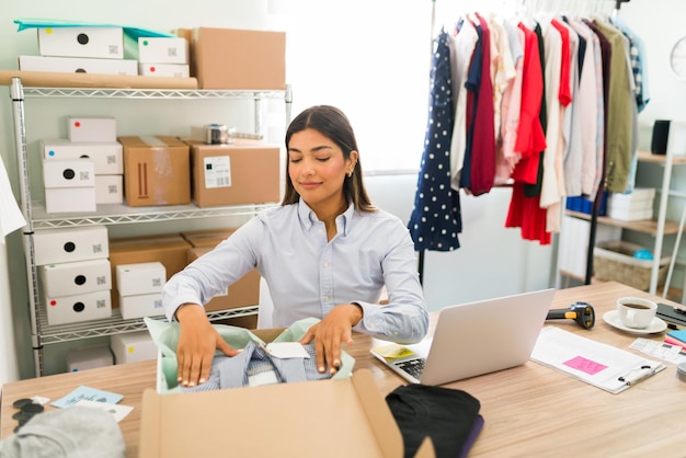 Foto gratuita mi negocio de la moda se está expandiendo rápidamente. la dueña de una empresa hispana se siente orgullosa de su nueva empresa y de su tienda de ropa en línea