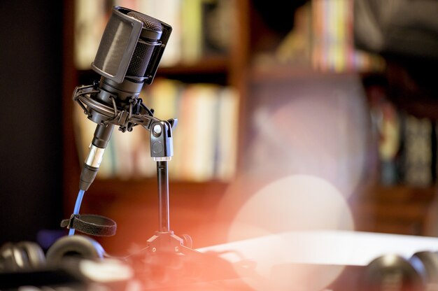 Micrófono en un estudio rodeado de equipos bajo las luces con un fondo borroso