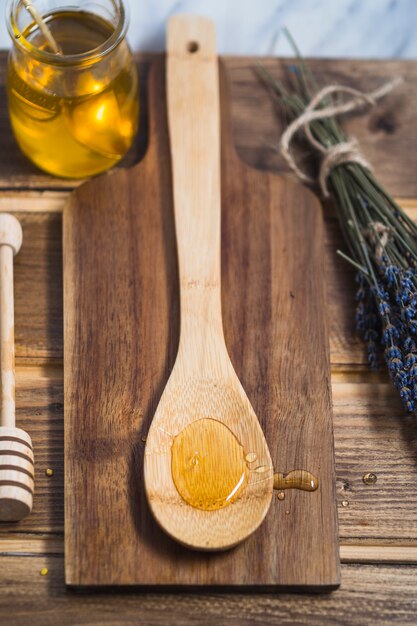 Miel en una cuchara de madera sobre la tabla de cortar