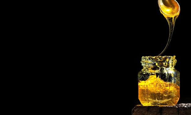 Miel natural orgánica, iluminada por la luz del sol, en un frasco de vidrio