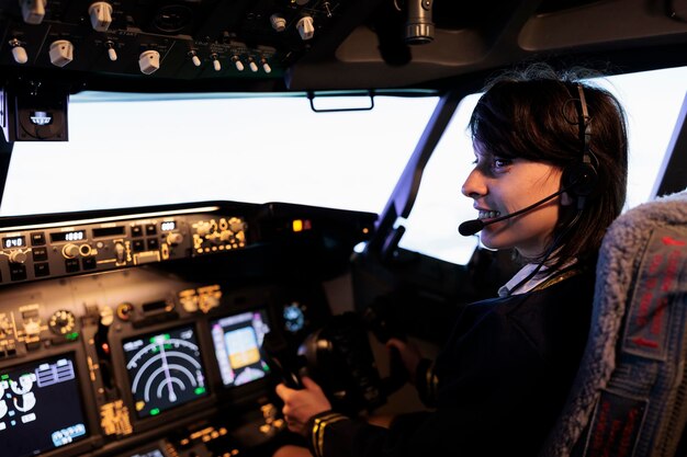Miembro de la tripulación que vuela en avión desde la cabina con panel de mando y control en el tablero, utilizando el volante y el panel de control para la navegación en el parabrisas. Mujer que usa la palanca para volar aviones.