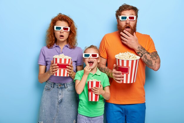 los miembros de la familia disfrutan viendo la televisión con palomitas de maíz