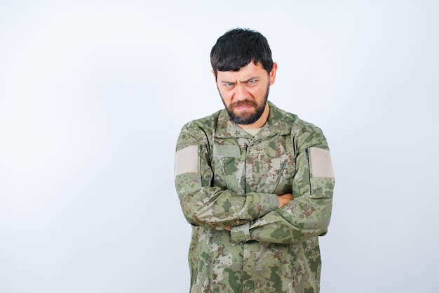 Un militar enojado está mirando a la cámara cruzando los brazos con fondo blanco