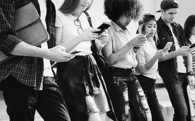 Foto gratuita millennials que usan teléfonos inteligentes al aire libre juntos