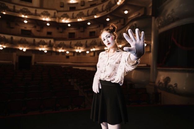 Mime femenino que se coloca en el auditorio que muestra gesto de la parada