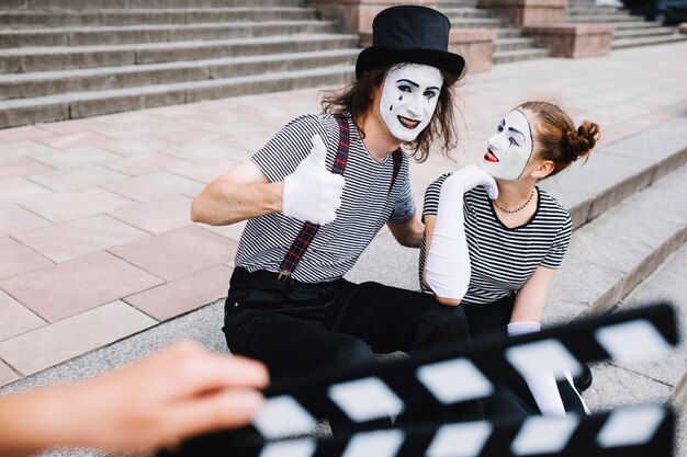 Mime femenino que mira el mime masculino que gesticula los pulgares para arriba