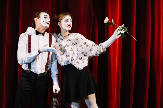 Mime femenino que sostiene la rosa blanca que se coloca con el mime masculino