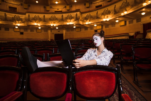 Foto gratuita mime femenino sentado solo en el auditorio leyendo el manuscrito